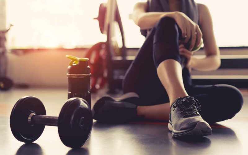 Woman sitting next to barbell at the gym